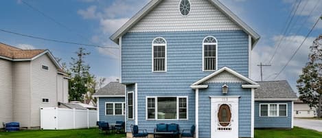 A blue and white house perched on a lush green field, like a fairytale cottage.