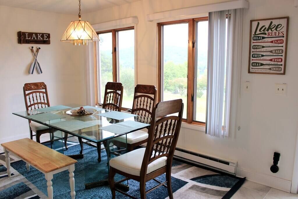 Dining room with windows opening onto the lake and the surrounding grass.