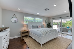 Luxurious Master Bedroom with King sized bed with crisp whites and touches of coral. En-Suite private bathroom, Smart App Roku TV and direct access onto the pool deck.