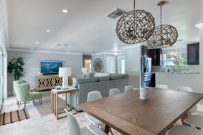 Gorgeous open plan living and dining room area with 10 seater gorgeous wooen table with low hanging rustic light fixtures and direct access to the pool deck.