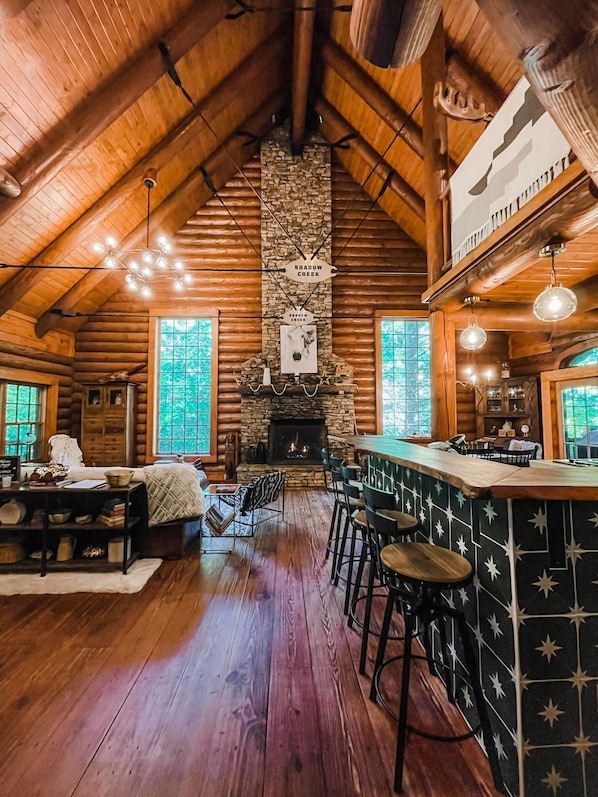 Main living area with soaring ceilings and stacked stone gas-burning fireplace.