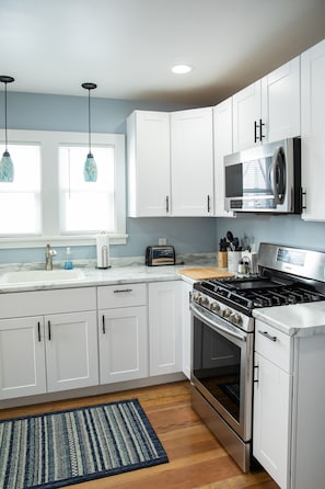 Gas range with microwave. Kitchen sink with disposal and pendant lights.
