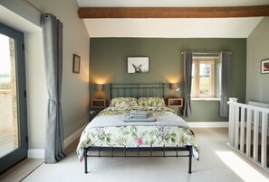 First floor: King- size bed with exposed beams and doors leading out to the balcony