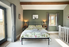 First floor: King- size bed with exposed beams and doors leading out to the balcony