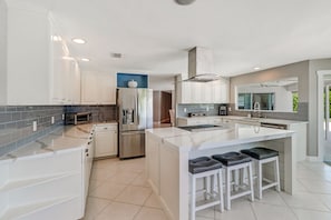 Modern kitchen with stainless appliances and seating for 3 at island.