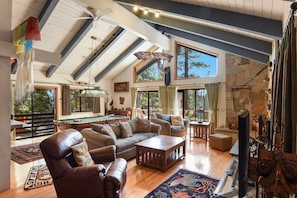 Living room with pool table, large Smart TV, fireplace, and piano