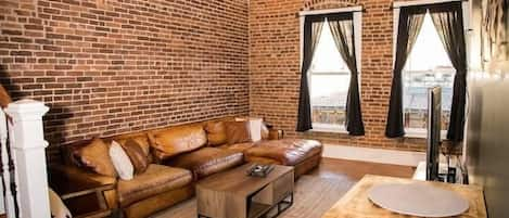 Gorgeous 1800s brick floods the living room. Large, comfy leather couch provides plenty of seating.