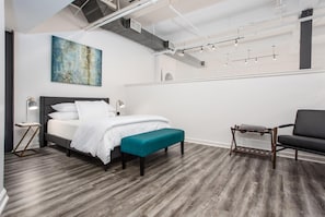 Retreat to the cozy lofted bedroom, featuring a plush bed, soft linens, and an intimate ambiance that offers a peaceful escape above the vibrant energy of downtown Fort Worth.