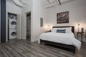 Retreat to the cozy lofted bedroom, featuring a plush bed, soft linens, and an intimate ambiance that offers a peaceful escape above the vibrant energy of downtown Fort Worth.