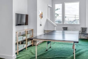 Hangout room downstairs in the garage area with a ping pong table and Smart TV.