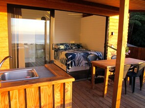 Terrasse couverte avec cuisine équipée, espace repas et l'entrée de la chambre