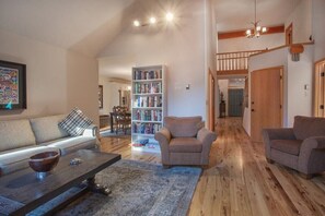 Main living area with kitchen in background on left and entry way and catwalk in background on right