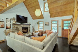 Walk in to a vaulted ceiling room with fireplace, 70" TV and comfy furniture