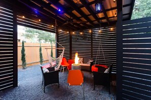 Covered Patio With Fire Pit And Hanging Chairs For Relaxation