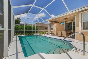Fully screened pool area with loungers and outdoor dining and TV