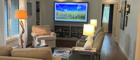 86" TV anchors living room for movies or sports.  Cabinet below w/games.