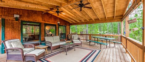Covered area of deck with ceiling fans and cushioned wicker furniture.