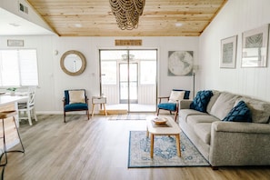 Living room set up with a view out to the water and screened in porch