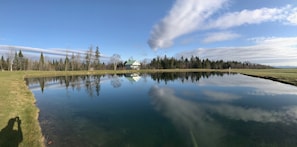 View of the cabin and brilliant blue sky reflected in the stillness of the pond