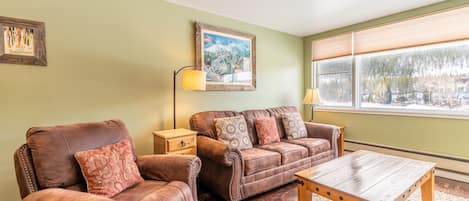 Living area with hardwood flooring, gas fireplace, queen size sleeper sofa and beautiful lake views.