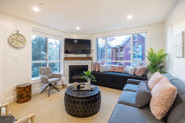 A spacious living room that can seat 4 guests while enjoying the view outside and warmth from the fireplace