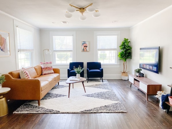 Living room features a cozy setup with smartTV, lots of open space for play along with a playmat (under the sofa) and books and games!