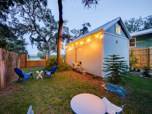 Private garden with dining setup, string lights, and lounge chairs.