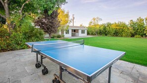 Outdoor ping pong table next to the pool, soccer field, & gym house