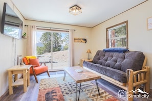 Living room with cozy, rustic furnishings and a mounted 43” widescreen SmartTV.