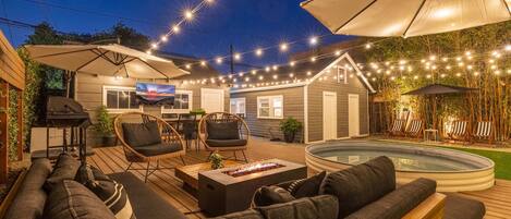 Large and lush private backyard with spacious 30 ft deck, resort lounge furniture, cantilever umbrellas, smart market lights, outdoor smart tv, firepit, and heated pool/hot tub.
