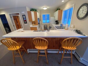 A fully equipped kitchen with a breakfast bar for three