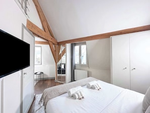 Comfortable Queen-size bed, flat screen TV, and storage space included in the room.