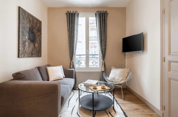 Spacious living room full of light with TV and double sofa.