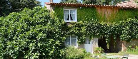 Façade avant du gîte avec petit salon de jardin.