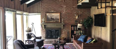 Living room with high ceilings and a wood burning fireplace in the chalet