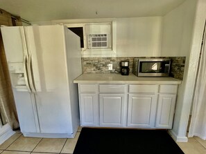 Full refrigerator, microwave, coffee maker, toaster, hot plate, and dish wear 