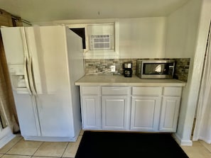 Full refrigerator, microwave, coffee maker, toaster, hot plate, and dish wear 
