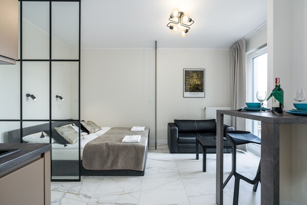 A modern living room with a beige sofa, stylish coffee table, and large window, offering plenty of natural light.