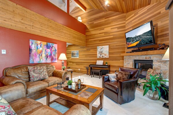Living Room with plush leather furnishings, 50" TV, gas fireplace, piano, wall-mounted stereo system, and private balcony access