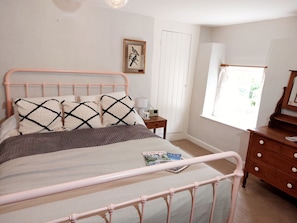 Master bedroom with kingsize iron bed and views over the garden