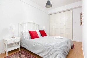 Stylish bedroom with white bedding and vibrant red pillows.