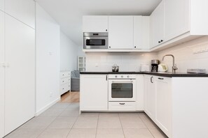 Open kitchen with white cabinets and stainless-steel appliances.