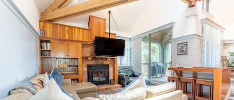 Living area featuring vaulted ceilings, fireplace, and cozy furnishings.