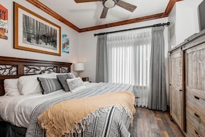 Cozy bedroom with king bed, window view, cabinet, and lampshades.