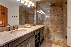 Double sink, mirror, rain shower, and cozy bench.