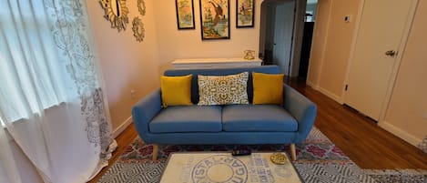 This cozy living room features eclectic furnishing and big sunny windows.