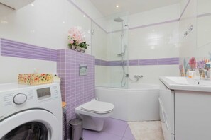 A clean and contemporary bathroom featuring purple tiles, a white sink, and a bathtub.