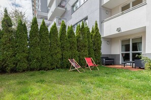 A private garden area with green grass, trees, and two relaxing deck chairs, perfect for outdoor leisure.