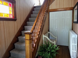 Private foyer with original stained glass & wooden stairway. Seating & closet.