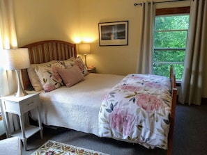 Cozy bedroom with queen-size bed and side chair. Overlooks backyard & river.